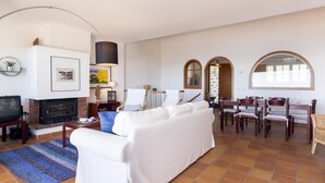 A living room with a fireplace, white sofa, dining table with chairs, and a TV. - SAILOR HOUSE with SEA VIEWS (Tossa de Mar)