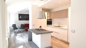 Et moderne køkken med en central ø, et spiseområde med stole og en rød sofa.