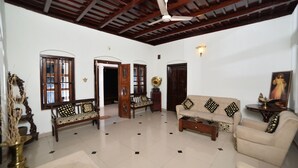 A spacious living area with a high ceiling, a ceiling fan, a sofa set, a coffee table, and a decorative vase. - Heritage Bungalow in Changanassery  (Changanassery)