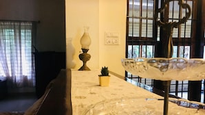 A room with a marble table, a small potted plant, a decorative glass object, and a window with bars. - Heritage Bungalow in Changanassery  (Changanassery)