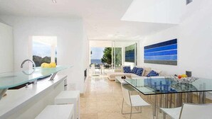 A modern kitchen with a glass dining table and white furniture. - House with direct access to the sea, pool and wifi (Santanyí)