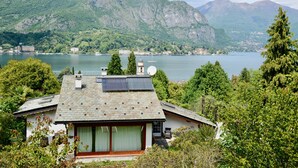 Une maison avec un toit en pente, des panneaux solaires et une vue sur un lac et des montagnes.