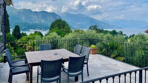 Une terrasse avec une table et des chaises, donnant sur un lac et des montagnes.