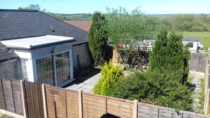 A residential property with a fenced backyard, a detached garage, and a house with a sloped roof. - Garden flat, dog friendly, sleeps 3/4, enclosed garden, parking, level access (Tiverton)