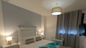A bedroom with a bed, nightstands, a lamp, a TV, and curtains. - 49 - Apartamento Sol Tarifa (Tarifa)