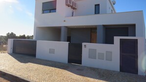 A modern two-story building with a flat roof, large windows, and a covered driveway.