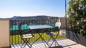 A balcony with a table and chairs, a view of a green field and distant buildings, and a mountain in the background. - Le Capannelle - Boheme by Feeling Italy (Massa Lubrense)
