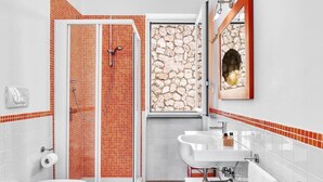 A bathroom with a shower, toilet, sink, and a stone wall. - Le Capannelle - Boheme by Feeling Italy (Massa Lubrense)