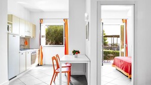 A compact kitchen with white cabinets, a dining table with two chairs, and a small window with curtains. - Le Capannelle - Boheme by Feeling Italy (Massa Lubrense)