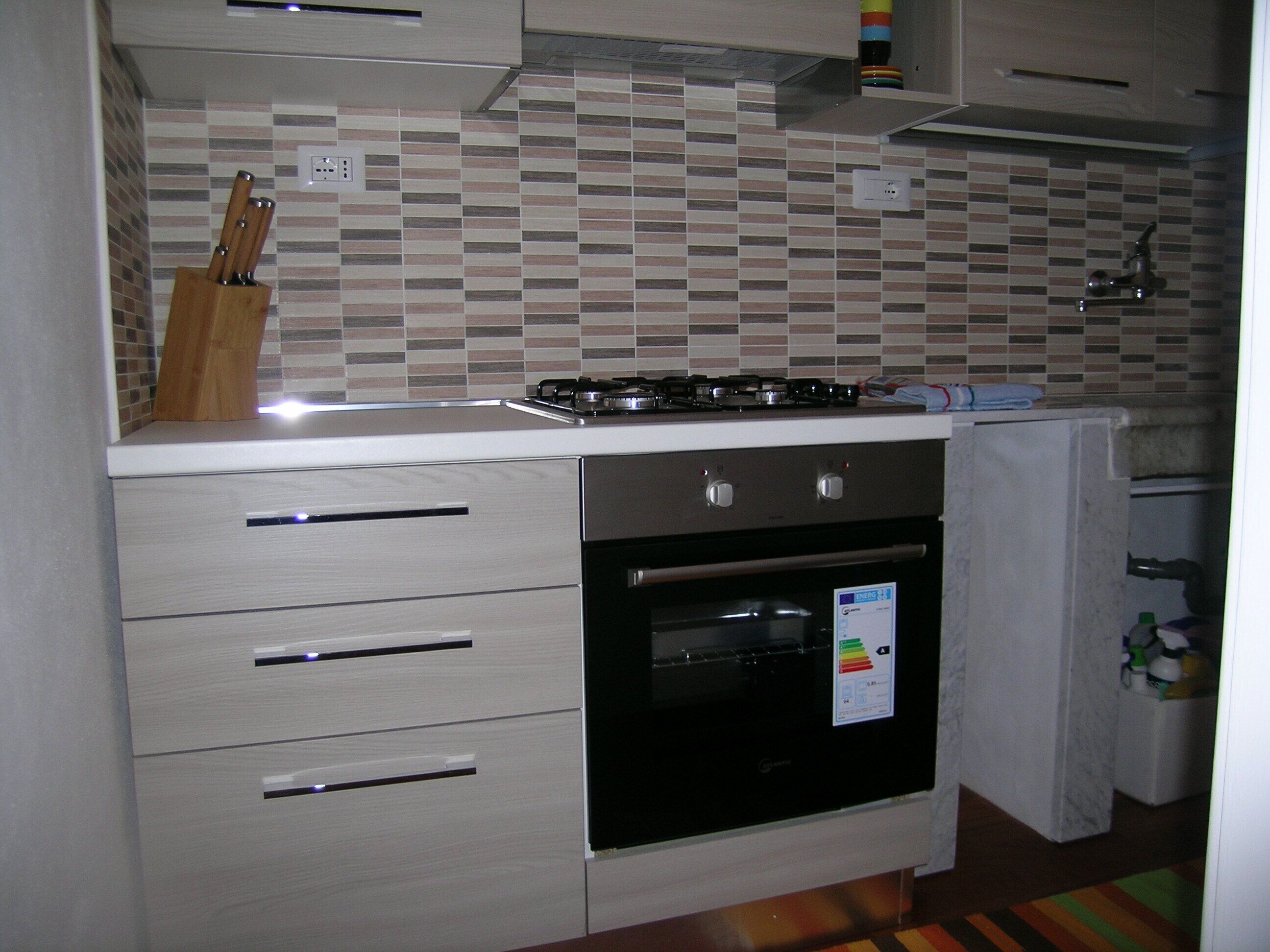Een keuken met een kookplaat, oven en een betegelde achterwand.
