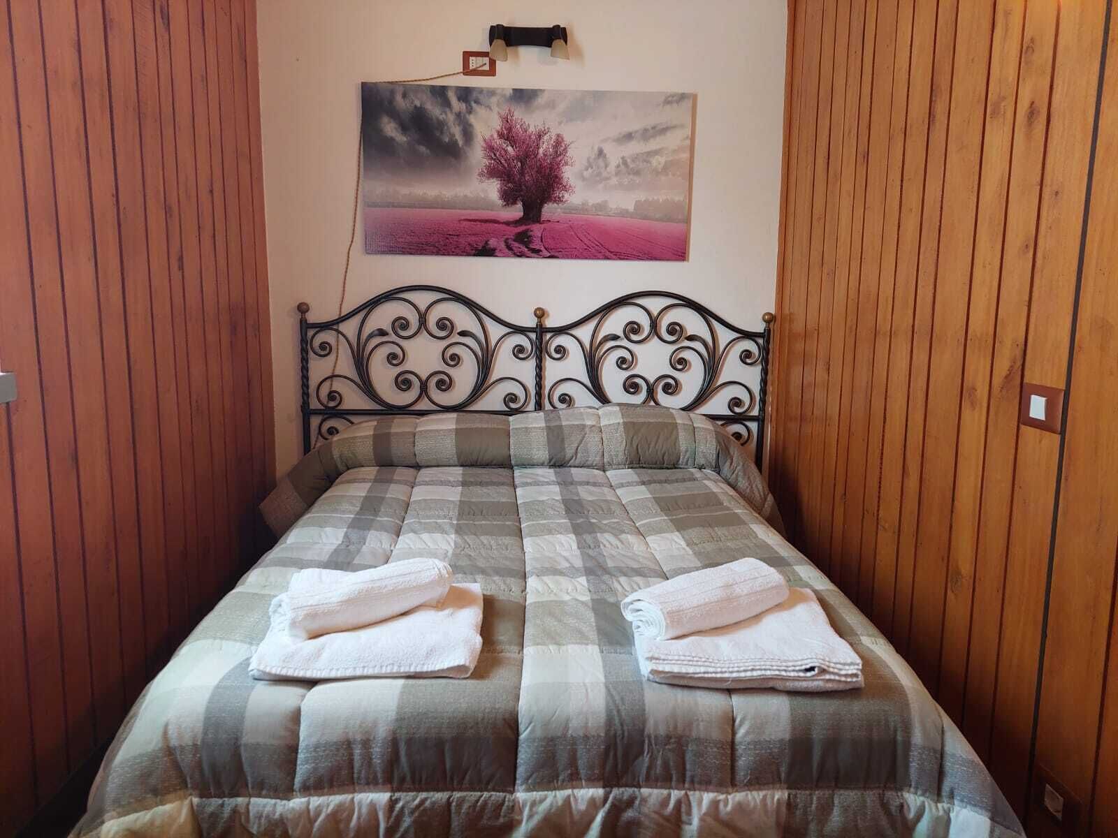 Ein Einzelbett mit karierter Bettdecke und zwei gefalteten Handtüchern.
