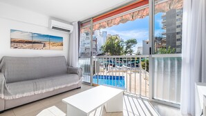 A modern living room with a sofa, a white coffee table, and a large window overlooking a pool and buildings. - Carabelas III 1-3 (Benidorm)