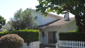 A house with a white exterior, a tiled roof, and a white picket fence.