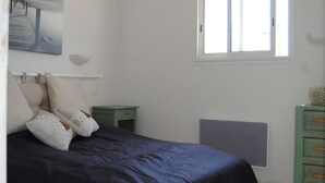 A bedroom with a bed, a nightstand, a dresser, a window, and a radiator.