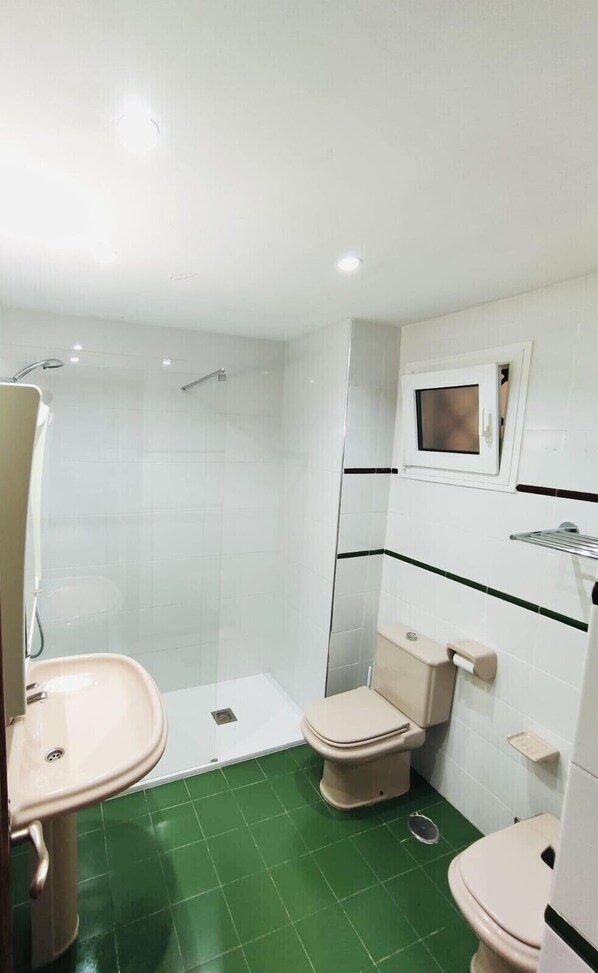 A small bathroom with a shower, a toilet, and a sink.