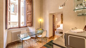 A compact kitchen with a glass table, a white chair, a radiator, and a microwave. - 1 Min to Pantheon – Designer 2BR Apt with 3 AC + Elevator (Roma)