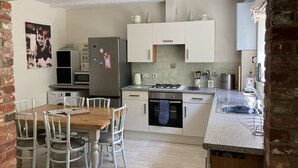 A compact kitchen with white cabinets, a stainless steel refrigerator, a gas stove, and a sink. - Edge of Old Village, close to shops, park and beach; ferry discounts (Shanklin)