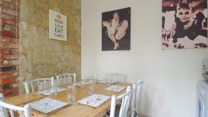 A dining area with a wooden table set for six, white chairs, and a sign on the wall. - Edge of Old Village, close to shops, park and beach; ferry discounts (Shanklin)