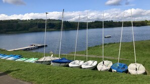 A lakeside view with several small boats docked along the shore, a grassy area, and a distant tree-covered landscape. - Central Apartment Linlithgow, near Edinburgh (Linlithgow)