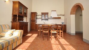 Cocina compacta con comedor, armarios de madera y piso de baldosas.