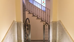 Eine Marmortreppe mit Metallgeländer, das zu einer Zwischenebene führt.