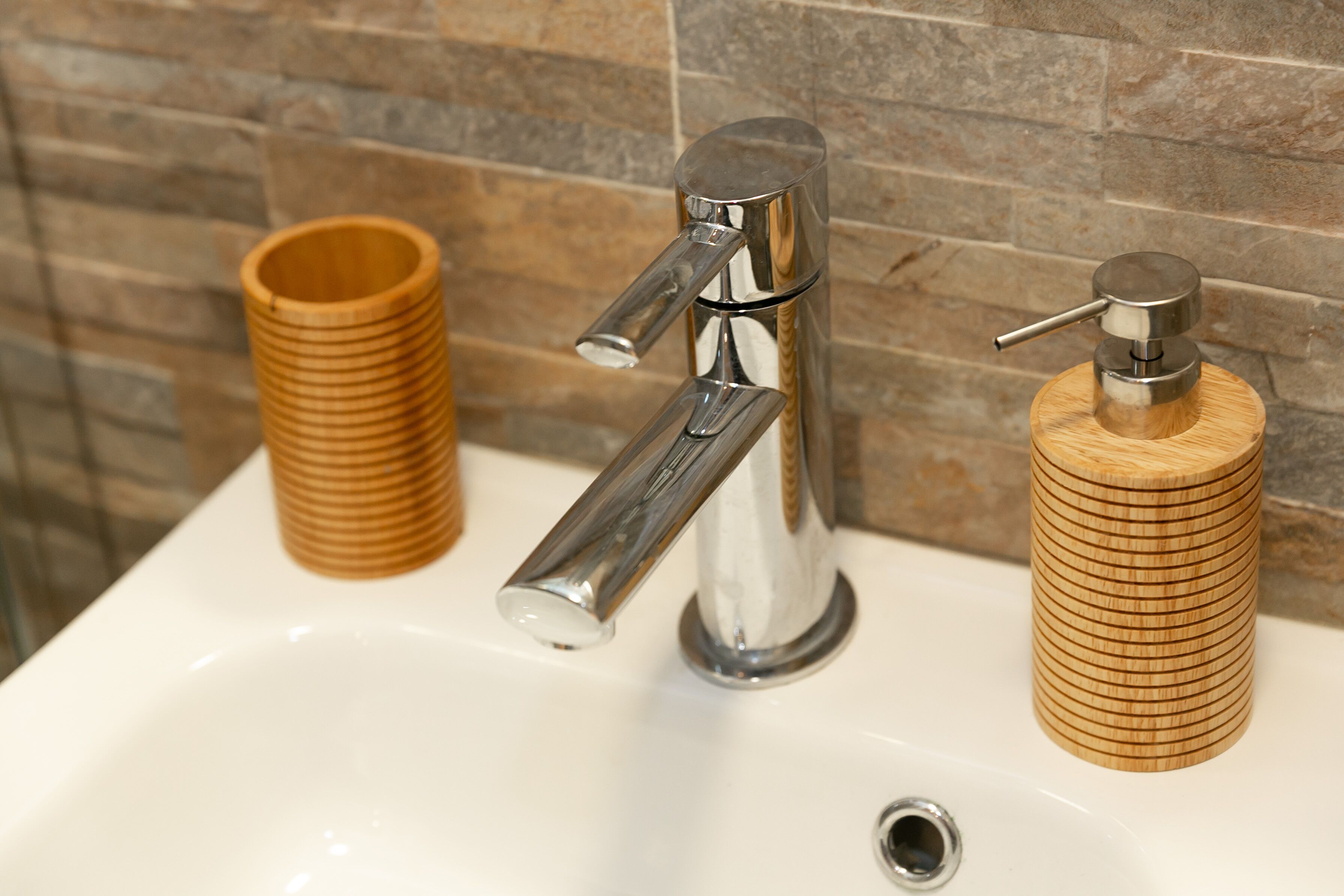 Ein Waschtisch mit einem modernen Wasserhahn und Holz-Seifenspender.