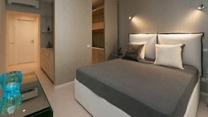 Ein Schlafzimmer mit einem Bett, Nachttischen, einem Kleiderschrank und einem Glastisch.