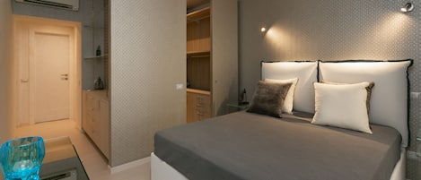 A bedroom with a bed, bedside tables, a wardrobe, and a glass coffee table.