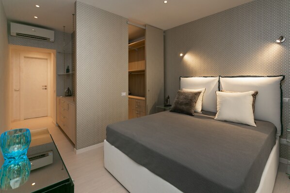 A bedroom with a bed, bedside tables, a wardrobe, and a glass coffee table.