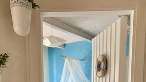 A bedroom with a bed, a canopy, a bedside table, and a wall-mounted decorative item.