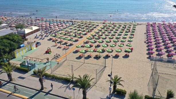 A beach with rows of umbrellas and chairs, a bike lane, and a pedestrian path.