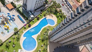 Vista aérea de un hotel con una amplia piscina, varias terrazas y vegetación circundante.
