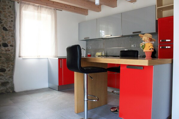 A modern kitchen with red cabinets, a wooden countertop, and a black chair. - The rose of the winds vacation home IT024097C2LMWLOL4M (Sarcedo)