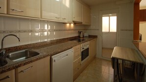 Une cuisine avec des meubles de couleur claire, un plan de travail en granit, un lave-vaisselle et une fenêtre.