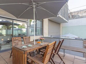 An outdoor patio with a wooden table and chairs, a large umbrella, and a view of the surrounding area. - Loft near the Sagrada Familia 6 pax Pool & Terrace -WiFi free (Barcelona)
