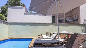 Une piscine avec des chaises longues et un parasol.