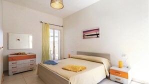Een slaapkamer met een bed, nachtkastje, dressoir, spiegel en een schilderij aan de muur.
