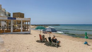 Een restaurant aan het strand met terras en uitzicht op de oceaan.
