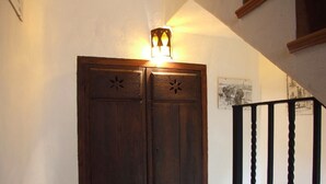 A wooden door with a light fixture above it, a black metal railing, and a framed picture on the wall. - Casilla Daleá, Andalusia center, Natural Park, by Planetrural (Carcabuey)
