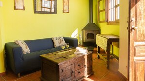 A room with a blue sofa, a wooden chest, and a wood-burning stove. - Casilla Daleá, Andalusia center, Natural Park, by Planetrural (Carcabuey)