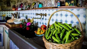 Una cocina con pared de piedra, salpicadero de azulejos y una cesta de verduras verdes sobre la encimera.