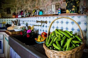 A kitchen with a stone wall, a tiled backsplash, and a basket of green vegetables on the counter. - Charming country house in the Florentine hills (Borgo San Lorenzo, Firenze)