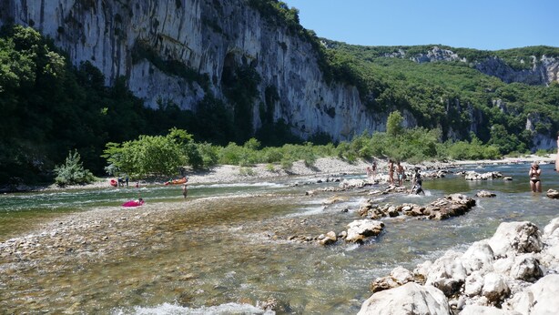 Une rivière aux eaux claires, aux rives rocheuses, avec une falaise en arrière-plan.