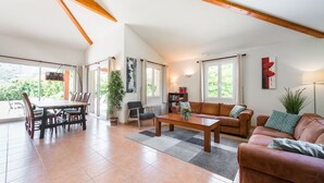 Un vaste espace de vie comprenant une table à manger, un canapé et une grande fenêtre offrant une vue sur l’extérieur.
