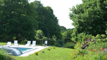 A swimming pool with lounge chairs and a grassy area with flowers.