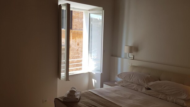 A bedroom with a bed, a nightstand, a lamp, and a window with blinds.