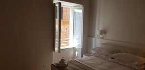 Une chambre à coucher avec un lit, une table de chevet, une lampe et une fenêtre avec des stores.