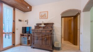 Un salon avec un meuble en bois, un téléviseur et une porte donnant sur une autre pièce.