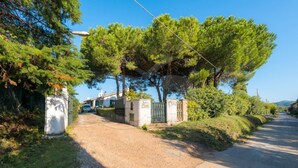 Une allée de gravier mène à une entrée fermée par un portail, et une voiture est garée à proximité.