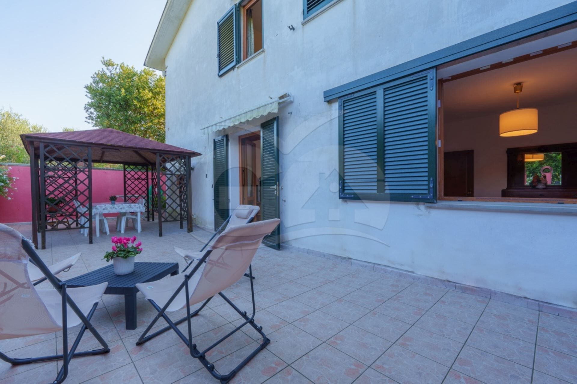A patio with outdoor furniture, a covered seating area, and a window with shutters.